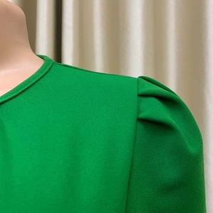 Detail van korte gepofte mouwen en geplooide schouder op groene getextureerde jurk