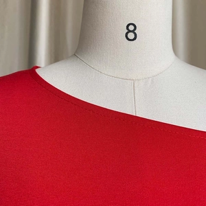 Primer plano de top de punto rojo con hombros descubiertos y cuello asimétrico