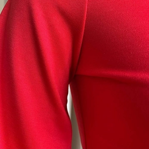 Primer plano de la textura de punto rojo y costuras de manga del conjunto de moda