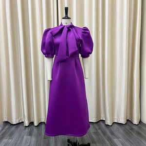Detail of elegant dark purple satin dress featuring a large bow and retro puff sleeves