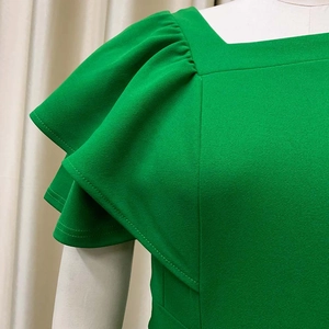 Detail of square neckline and layered ruffle sleeves on a vibrant green pleated dress