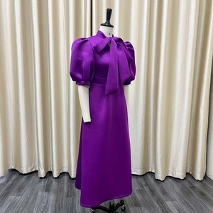 Detail of purple evening dress featuring a stand collar with bow tie and puff sleeves