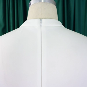 Close-up of a white dress with a hidden zipper and stand collar on a textured fabric