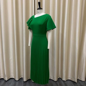 Detail of green summer dress featuring asymmetrical neckline and pleated skirt