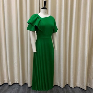 Detailed view of elegant green pleated maxi dress with ruffled shoulder and pleated texture