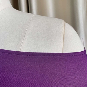 Primer plano de las costuras del escote y textura de punto fino en top violeta liso