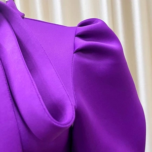 Detail of elegant puff sleeves with pleats on a violet evening dress with textured fabric