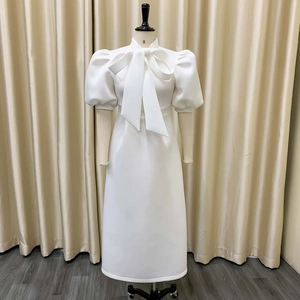 Detail of elegant white midi dress featuring a large bow neckline and puff sleeves