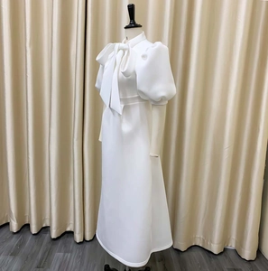 Detail of elegant white dress featuring bow neckline and puffy short sleeves design