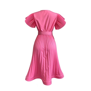Détail de la robe plissée rose pêche avec dos en V et ceinture à nouer assortie