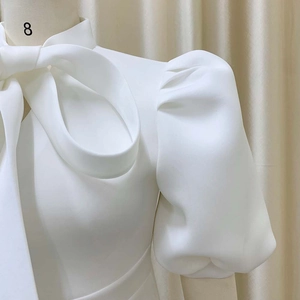 Detail of elegant white dress featuring a large bow neckline and vintage puff sleeves