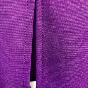 Primer plano de tela de punto morada con textura de tejido fino y detalles de costura