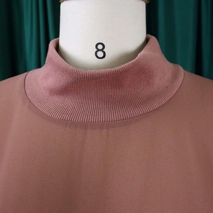 Detail van de geribbelde opstaande kraag op een elegante mauve chiffon tuniekjurk