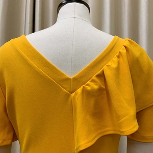 Detailed view of mustard yellow V-neck dress with elegant ruffle shoulder design