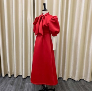 Detail of red elegant dress featuring a stand collar with a large decorative bow