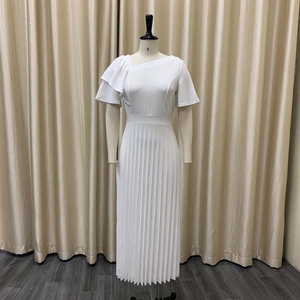 Detail of white one-shoulder dress featuring ruffled sleeve and pleated skirt on a mannequin
