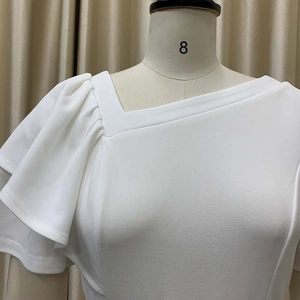 Detailed close-up of white dress with asymmetric neckline and ruffled sleeve layers