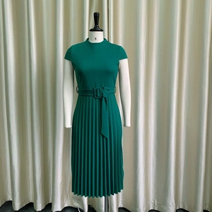 Détail d'une robe plissée vert foncé à manches courtes avec ceinture à boucle assortie