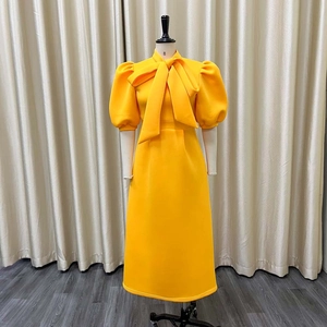 Detail of elegant yellow midi dress with puff sleeves and large bow neckline