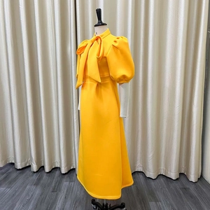 Detail of yellow midi dress featuring a large bow neckline and vintage puff sleeves