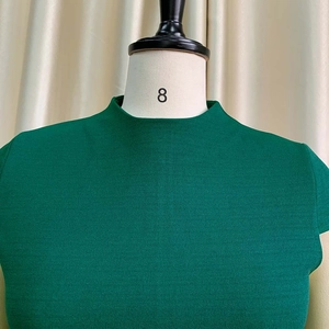 Détail d'une robe vert émeraude montrant le col montant et la texture du tissu tissé