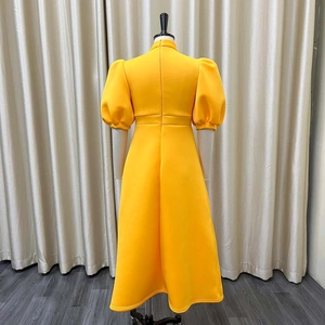 Detail of elegant yellow puff sleeve dress featuring a hidden back zipper and high waistline