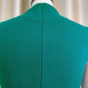 Gros plan sur la fermeture éclair invisible et le tissu texturé de la robe vert foncé
