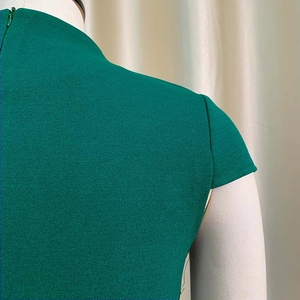 Détail du col montant et de la fermeture éclair invisible sur la robe vert foncé
