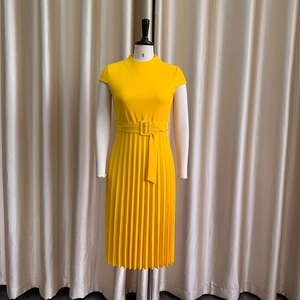 Détail de la robe plissée jaune vif avec ceinture à boucle carrée et texture de tissu ferme