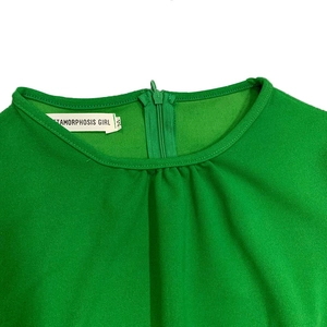 Detailweergave van de smaragdgroene ronde hals met verborgen rits en merklabel voor maat