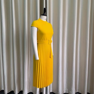 Détail de la robe plissée jaune à manches courtes avec ceinture et col montant