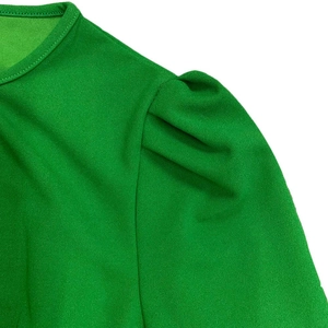 Detail van smaragdgroene geplooide korte mouwen en ronde halslijn van een zomerjurk