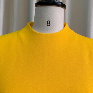 Détail du tissu de robe jaune vif à col montant avec une texture en mousseline fine