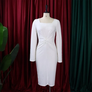 Détail de la robe blanche à col carré montrant le nœud à la taille et les perles