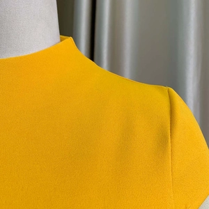 Détail de la robe jaune à manches courtes montrant l'encolure et la texture du tissu