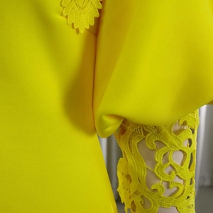 Detail of bright yellow dress featuring intricate lace lantern sleeves and smooth fabric