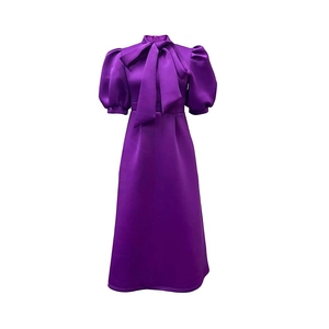 Detail of purple satin dress with elegant bow tie neck and puff sleeves on white backdrop