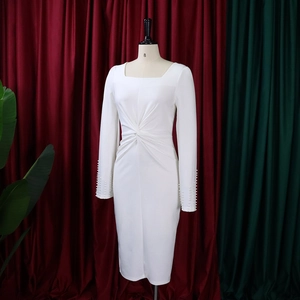 Détail de la robe blanche à col carré avec nœud à la taille et perles aux poignets