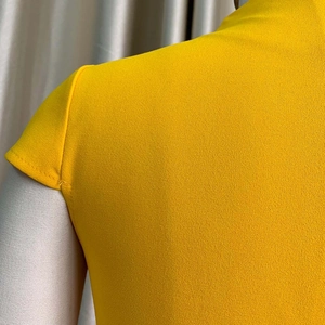 Gros plan sur la texture du tissu jaune et la couture d'épaule d'une robe d'été