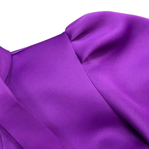 Close-up of shiny purple satin dress featuring puff sleeves and pleated shoulder texture