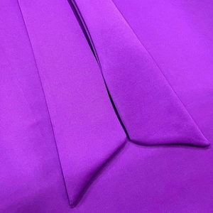 Close-up of refined purple woven fabric showing detailed edge stitching on the elegant dress