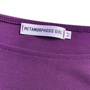 Primer plano del escote de punto morado con etiqueta de marca y talla M visible