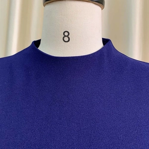 Gros plan détaillé du tissu texturé bleu foncé et des coutures d'une robe à col rond