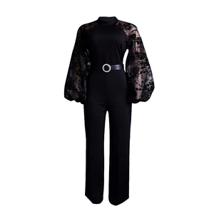 Detail of elegant black jumpsuit with sheer lace sleeves and a rhinestone belt buckle