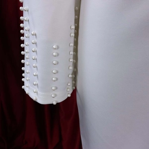 Détail de la manche d'une robe blanche avec des perles élégantes et tissu texturé