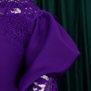 Close-up of intricate lace embroidery and ruffled lantern sleeve on a purple off-shoulder dress