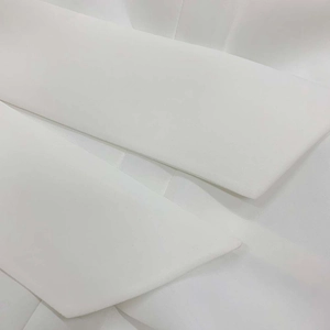 Detailed close-up of white dress bodice showing high-quality woven fabric and neckline texture