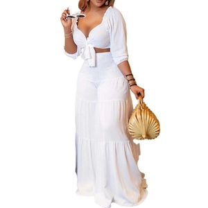 Detail of white deep V-neck crop top with bow tie and tiered high waist wide leg pants