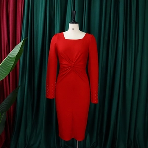 Détail de robe rouge à manches longues montrant les poignets perlés et la taille nouée