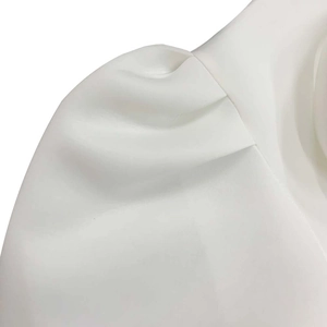 Detail of white satin dress featuring elegant pleated shoulder design and smooth fabric